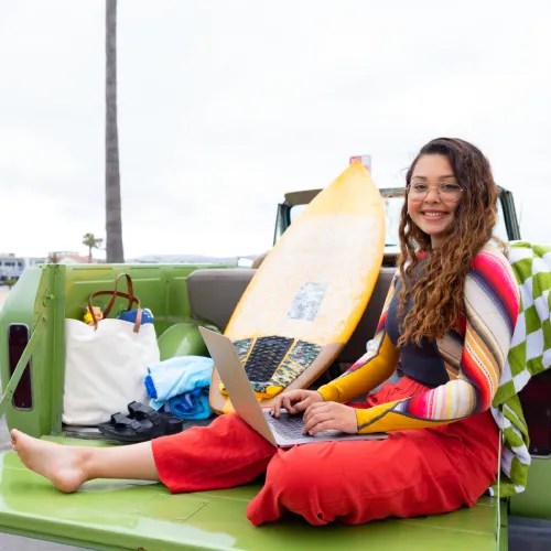 A woman sitting in the back of a truck with a laptop
