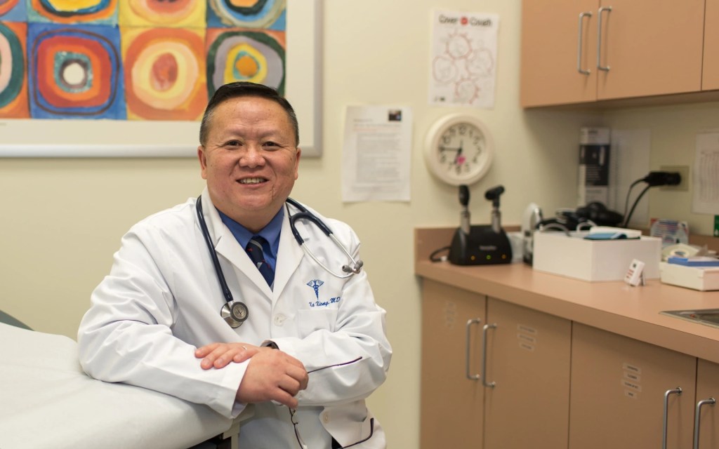 Concordia University Irvine health sciences professor in a medical office wearing a white coat and stethoscope
