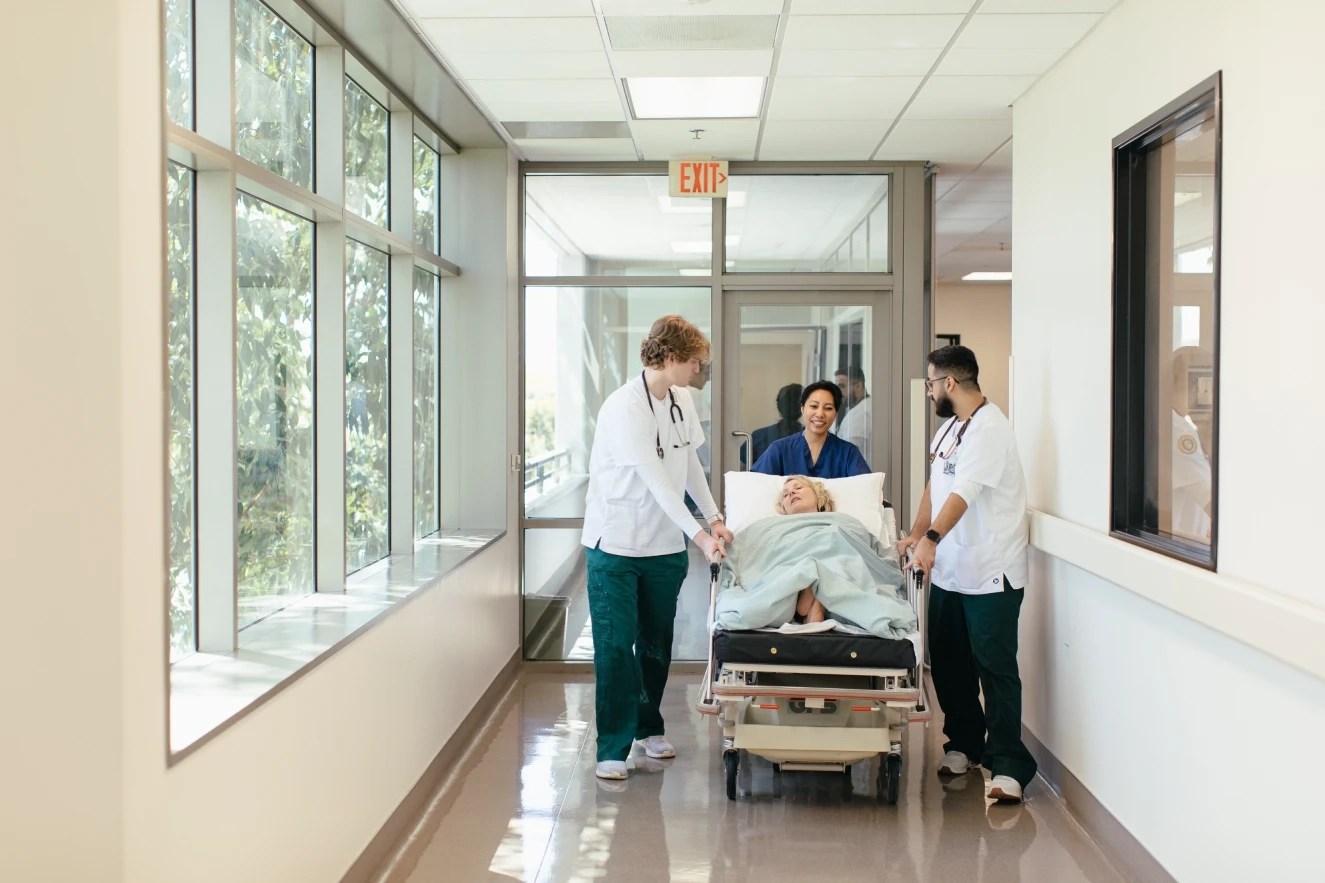 A group of people pushing a woman in a hospital bed