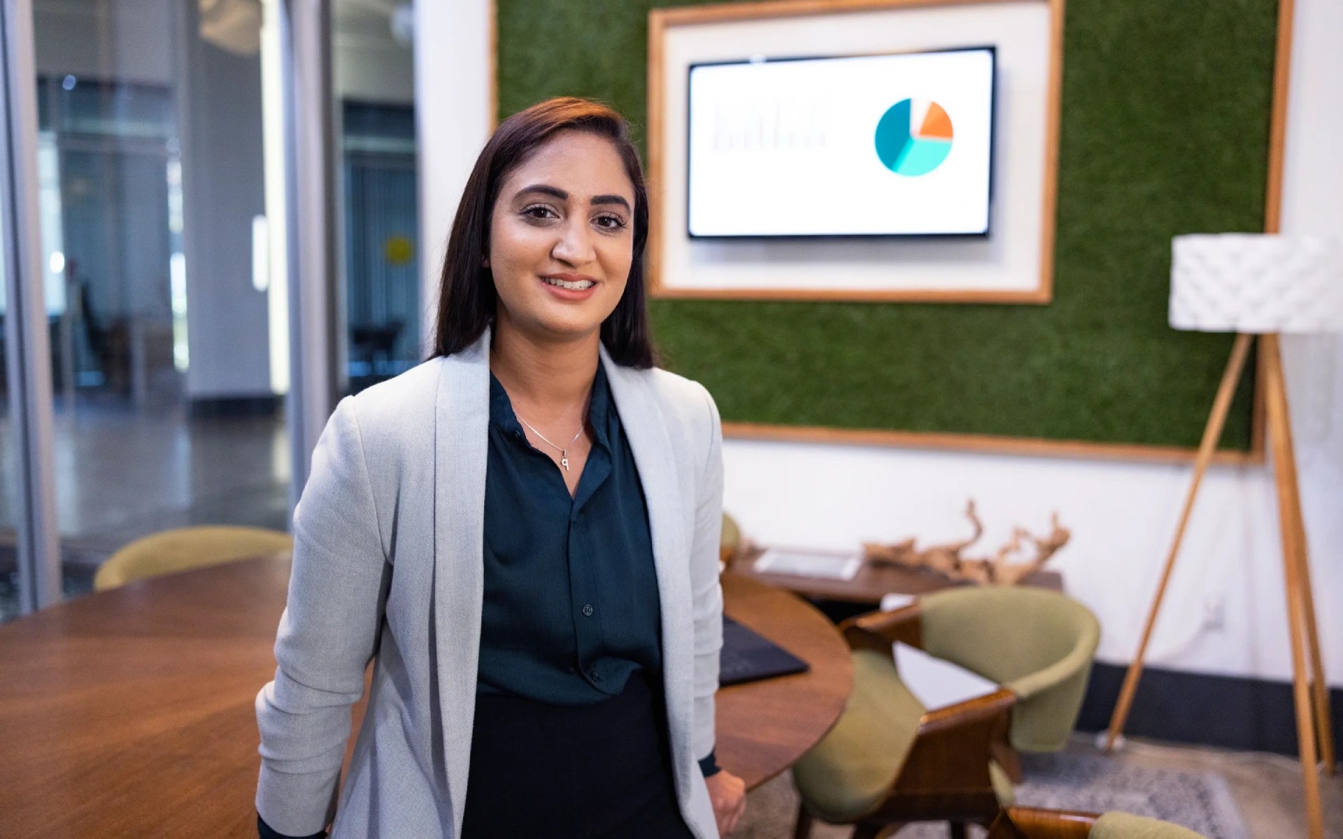 Concordia University Irvine student standing in a modern office space with a presentation screen in the background