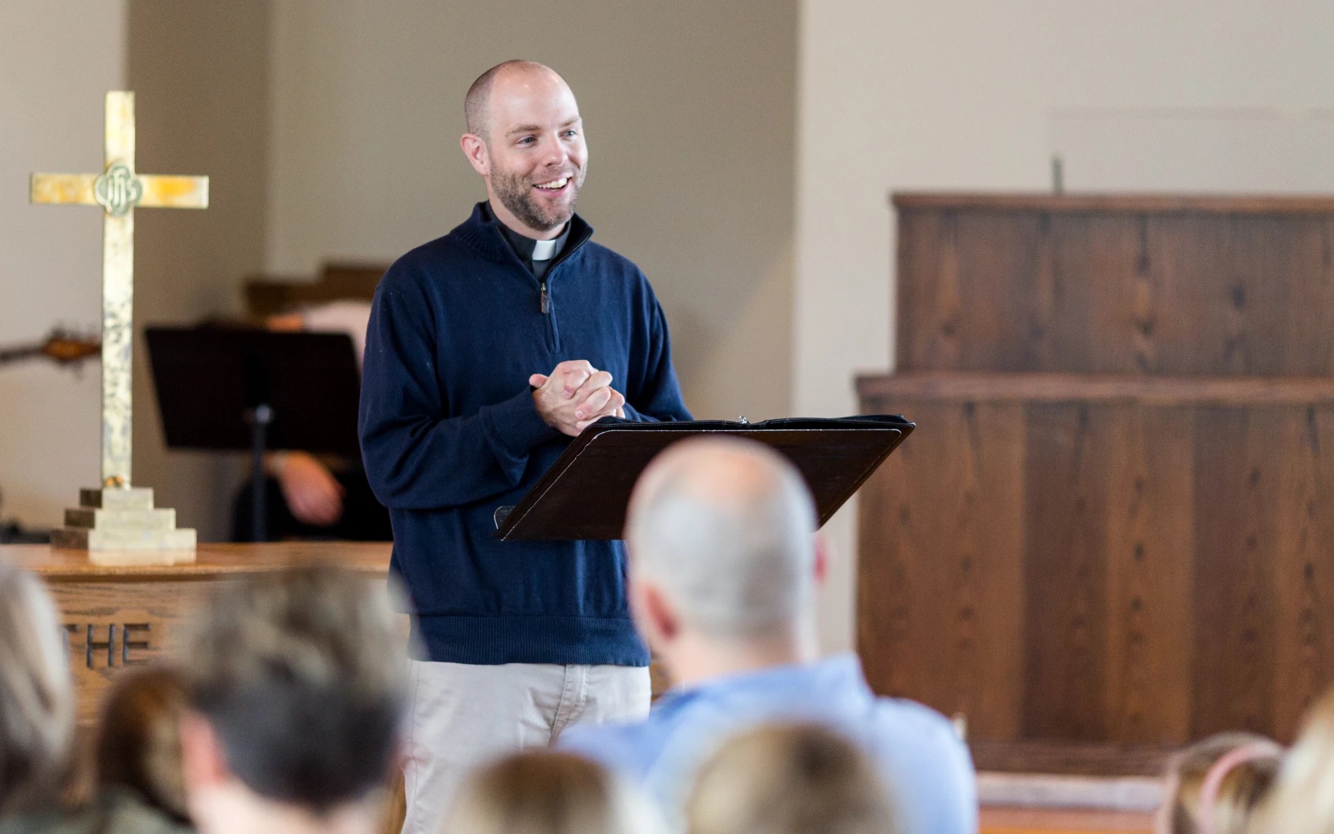 Speaker leading a chapel service at Concordia University Irvine with a cross on the altar in the background