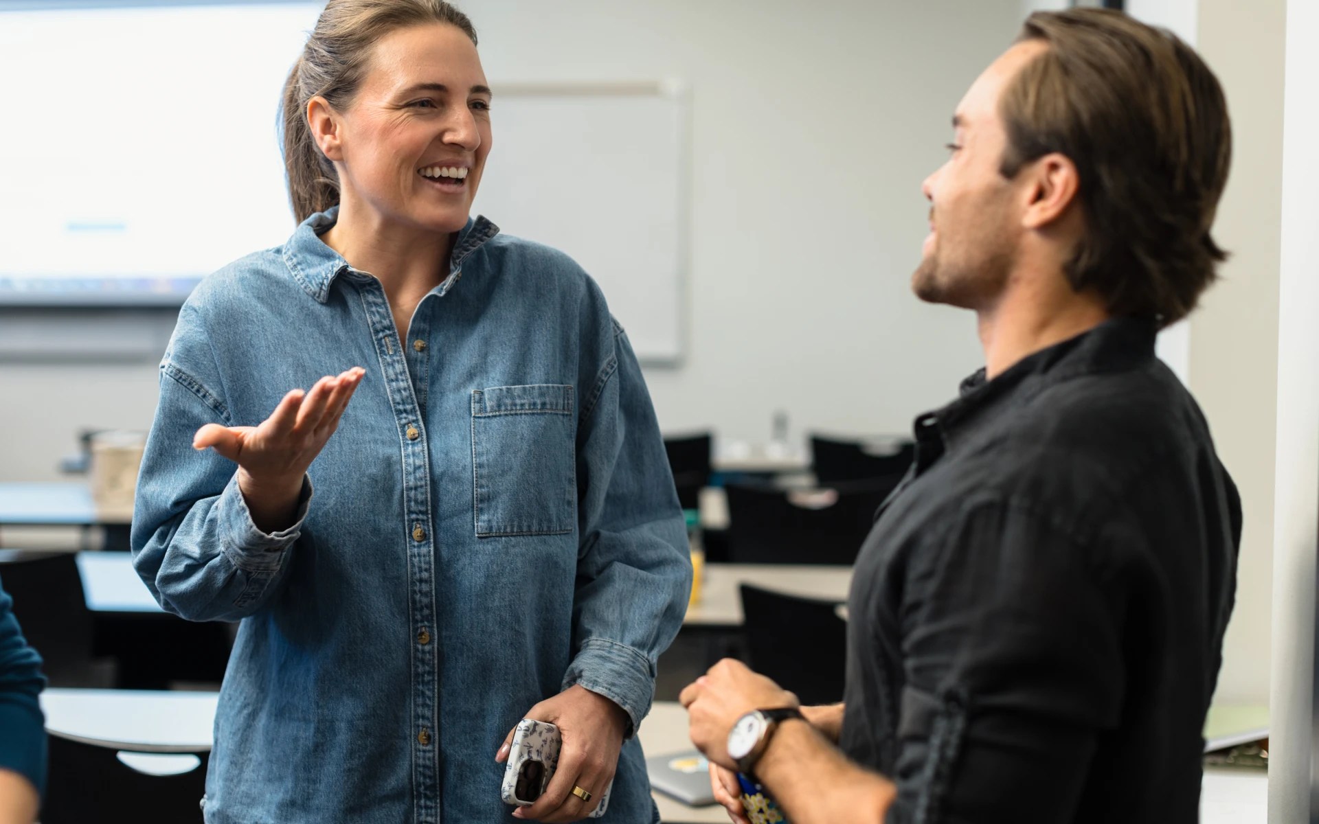 Two students talking and smiling during a discussion in a classroom at Concordia University Irvine