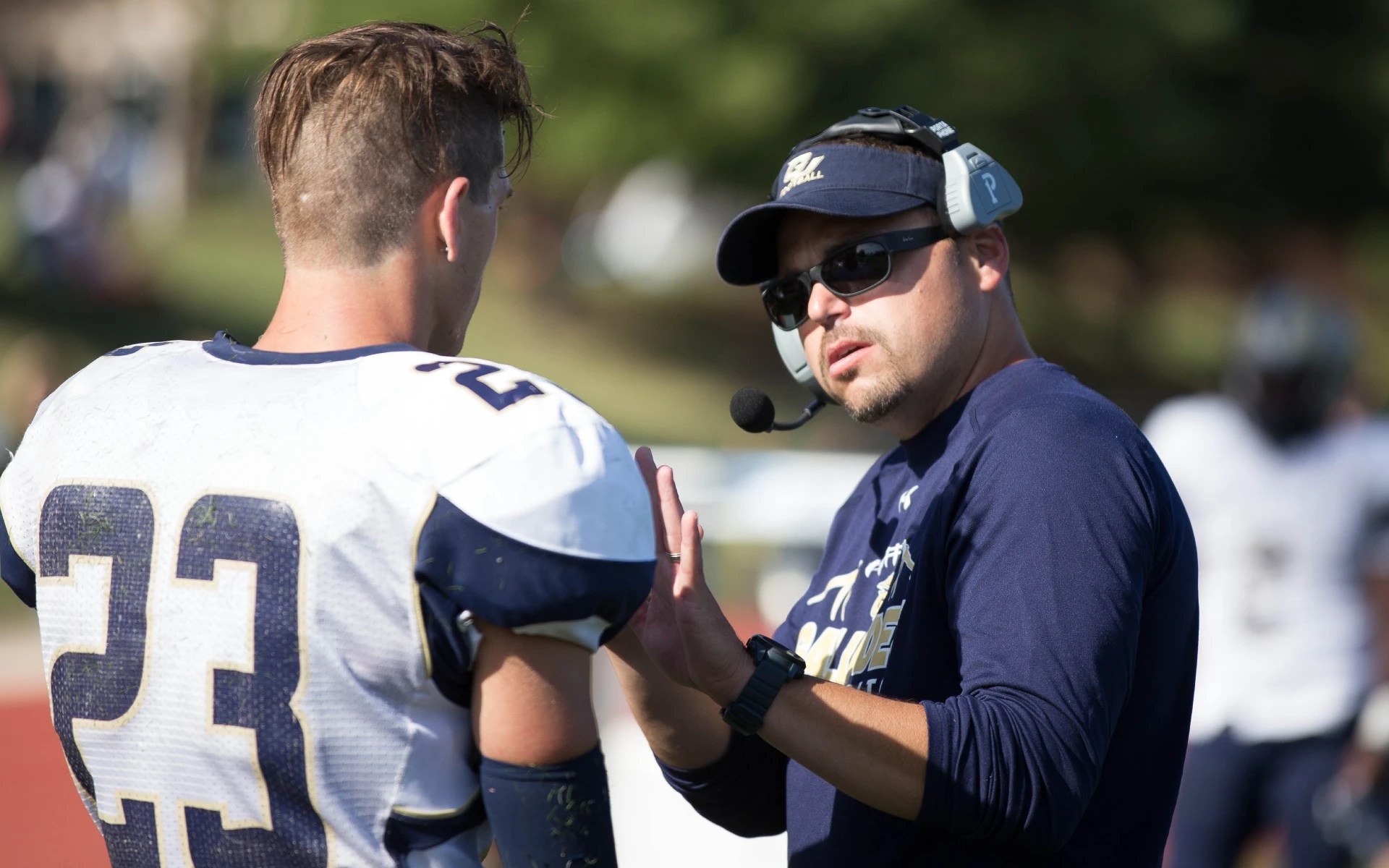 Football coach mentoring player during game
