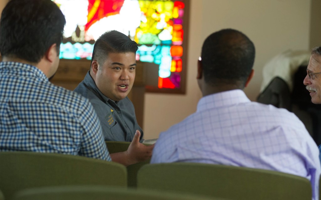 Concordia University Irvine student leading a small group discussion in a chapel with stained glass in the background