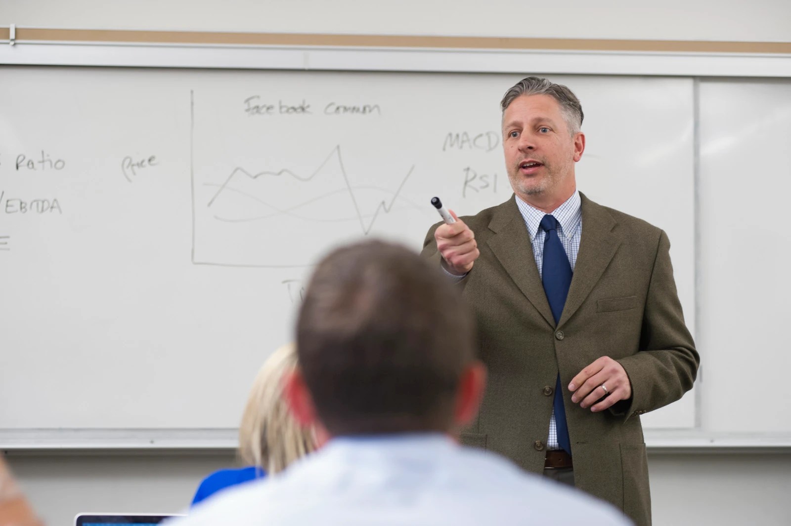 Professor giving a lecture and pointing to a whiteboard during class