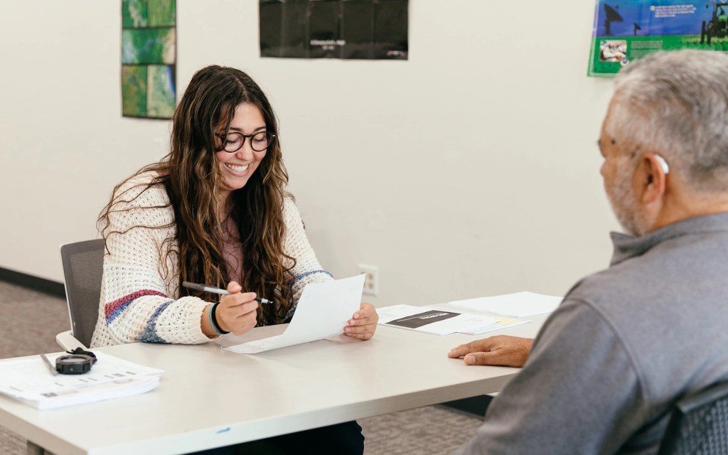 A counseling student smiles while reviewing a worksheet with an older adult during a practice session at Concordia University Irvine