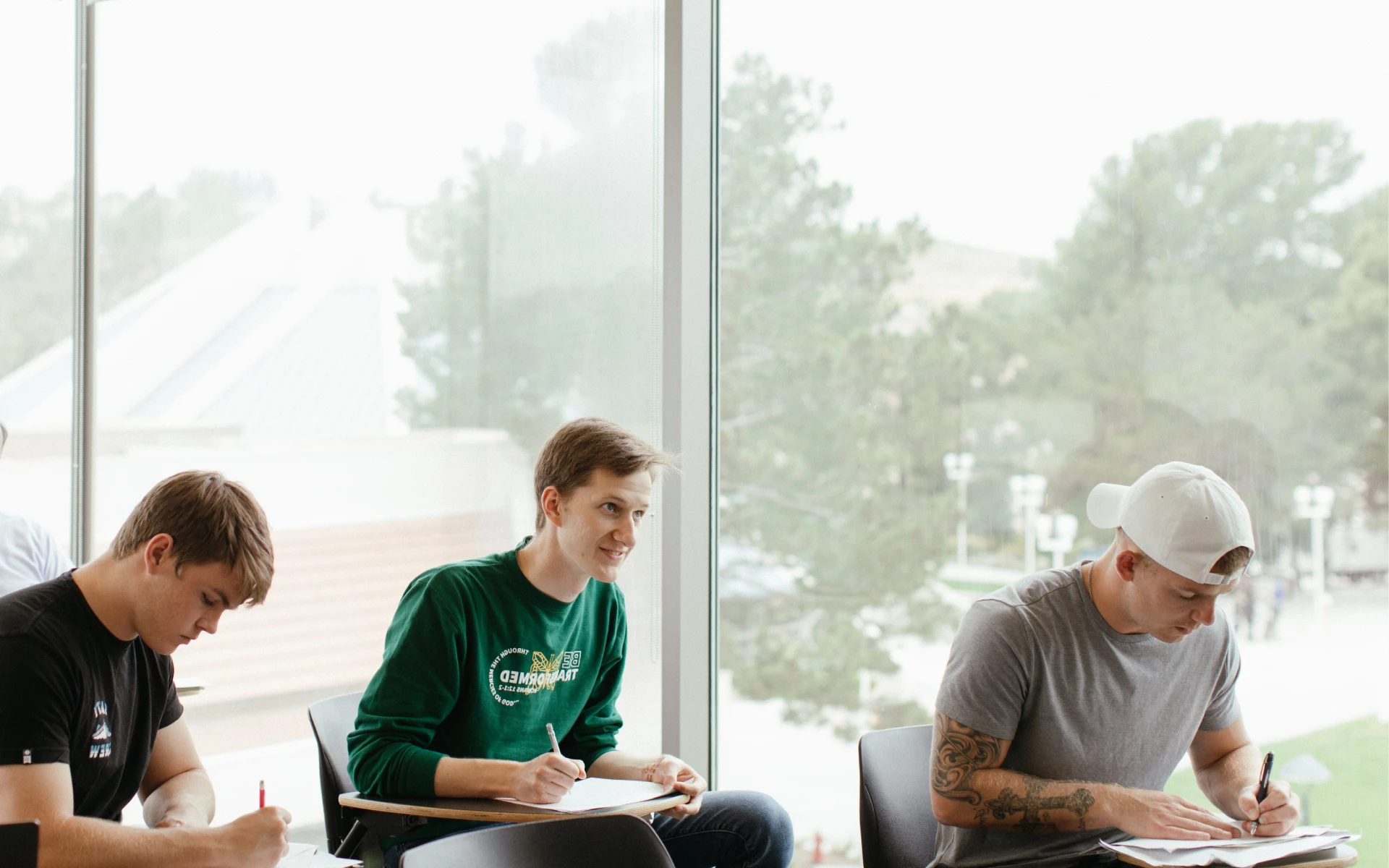 Students sitting by a large window taking notes during a class at Concordia University Irvine