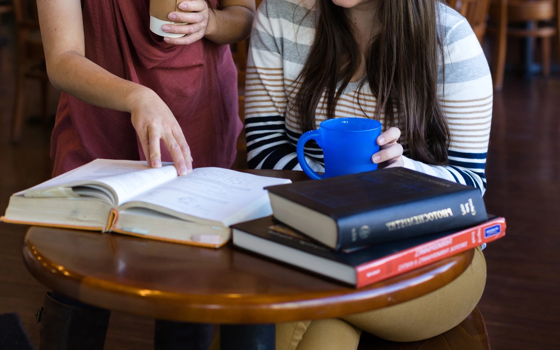 Concordia University Irvine students studying together at a campus coffee shop with books and coffee