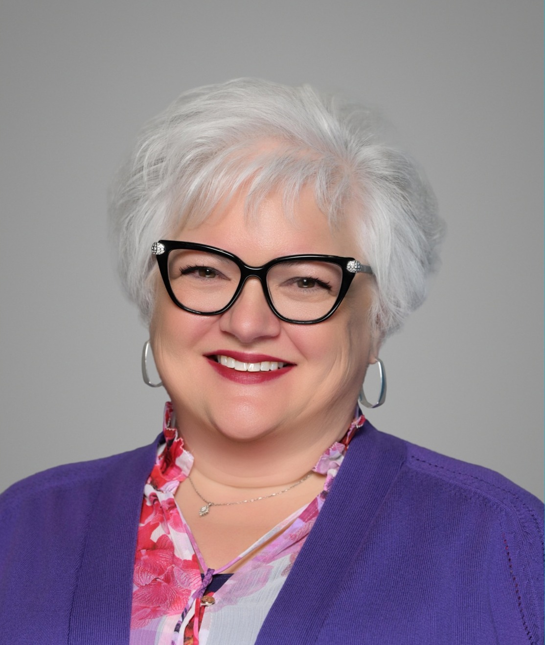 A woman with white hair wearing glasses