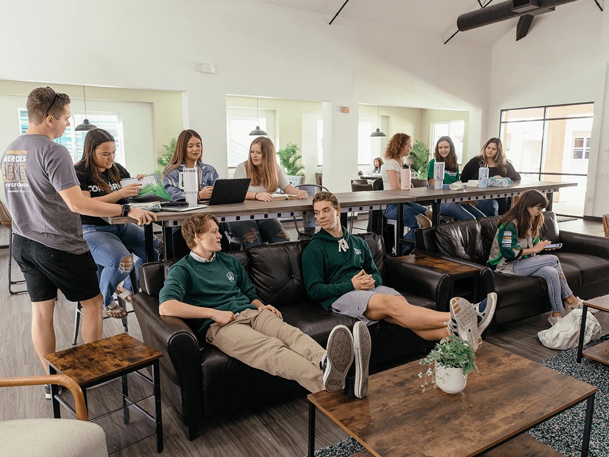 A group of people sitting on couches in a room with tables and chairs