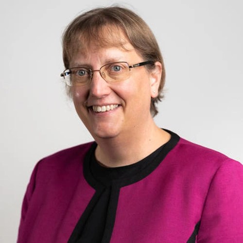 A woman wearing glasses and a purple jacket
