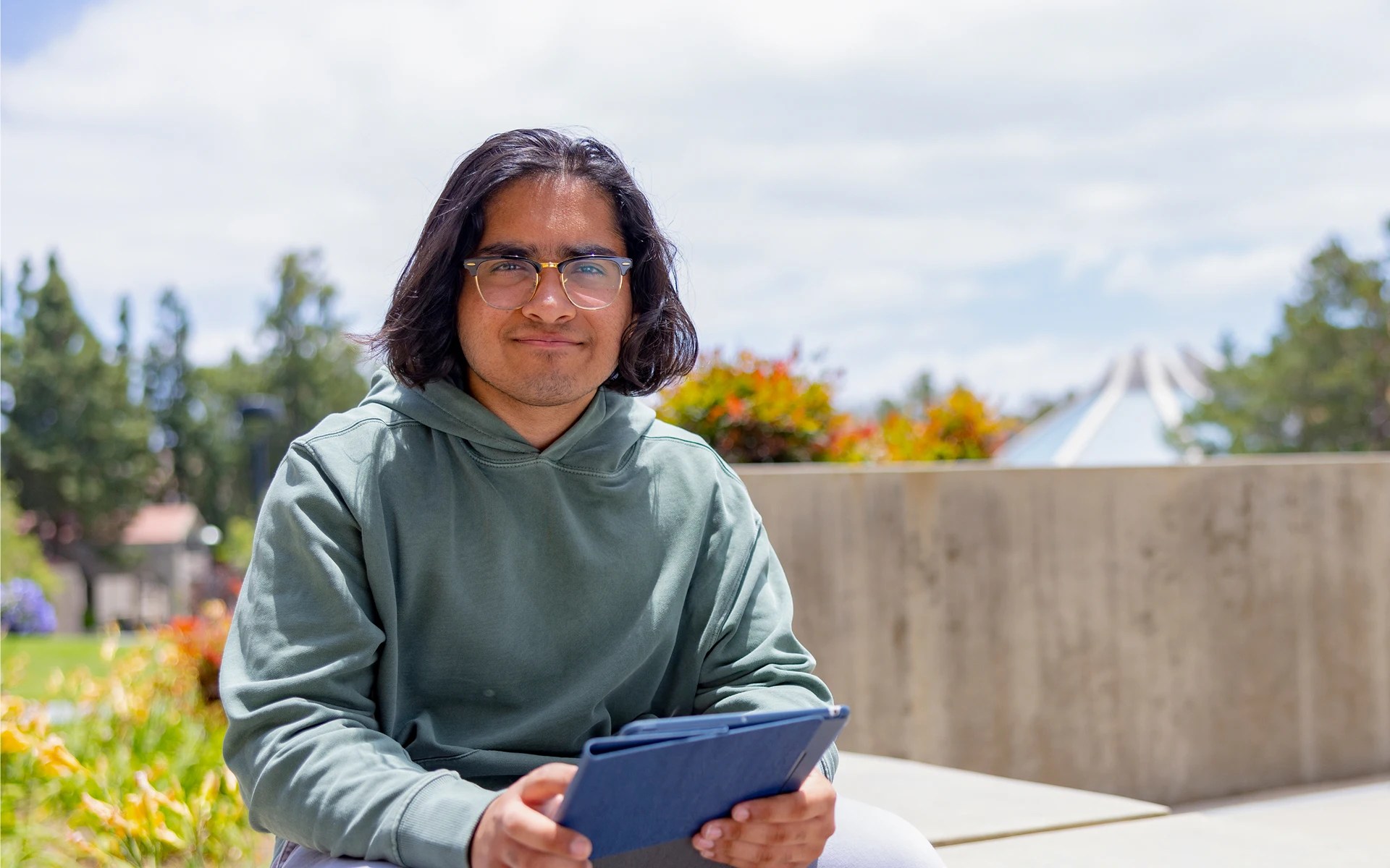 A man sitting on a bench holding a tablet