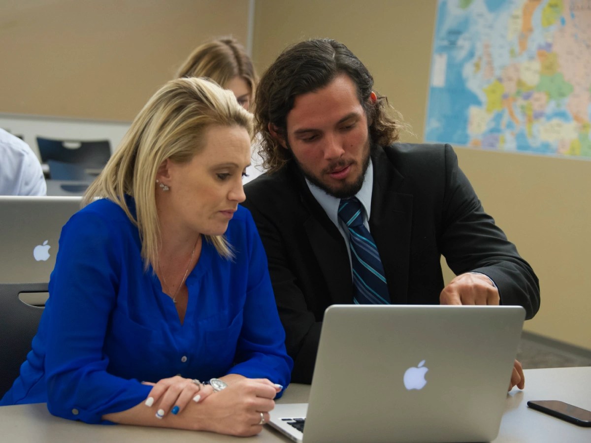 A man and woman looking at a laptop