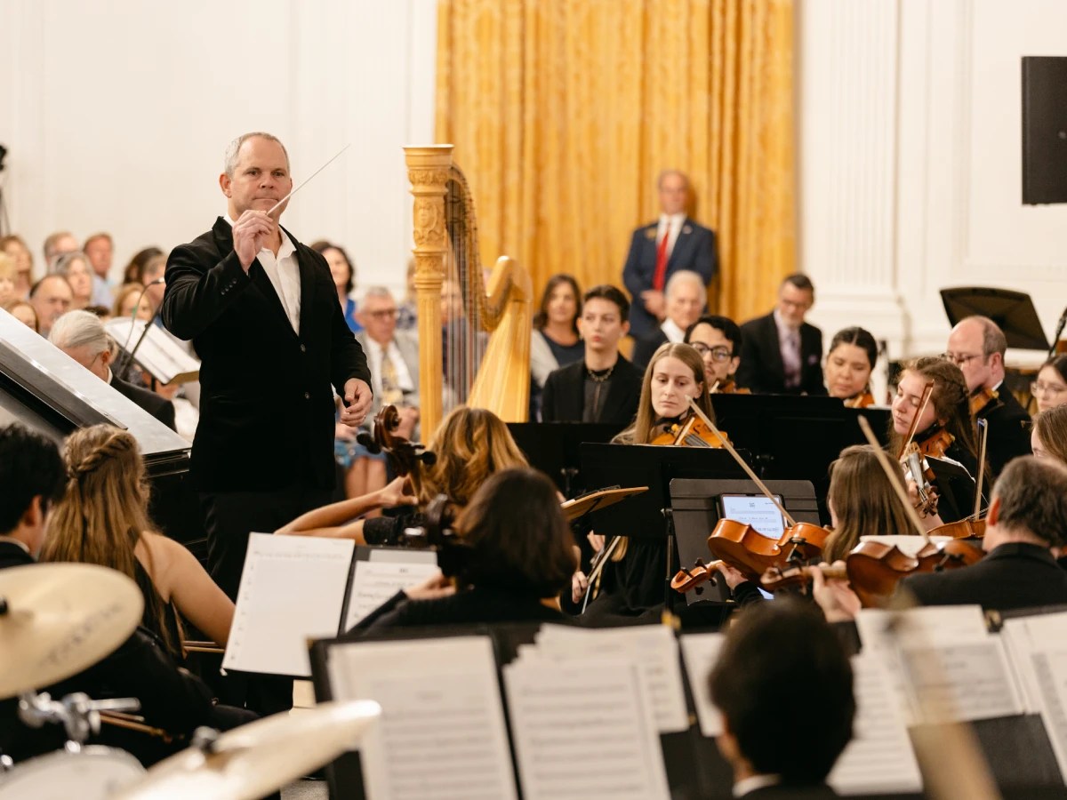 A man in a suit with a stick in front of a group of people