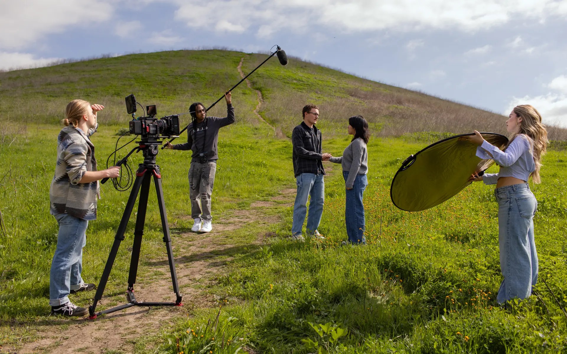 Students filming a scene outdoors using professional equipment including a boom mic and camera