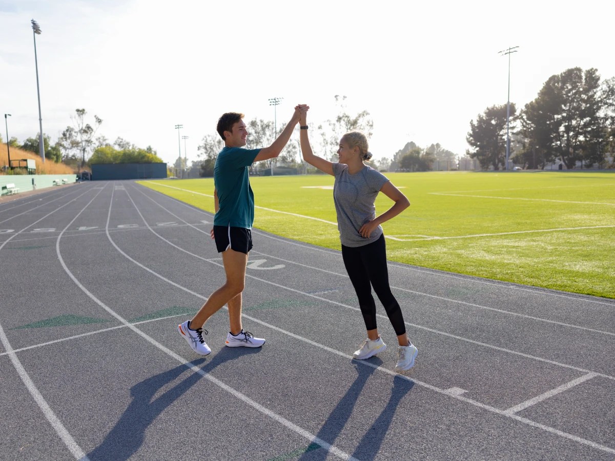 A man and woman on a track giving each other a high five