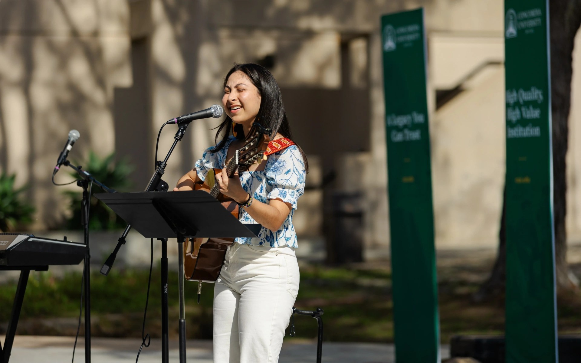 A woman playing a guitar and singing into a microphone