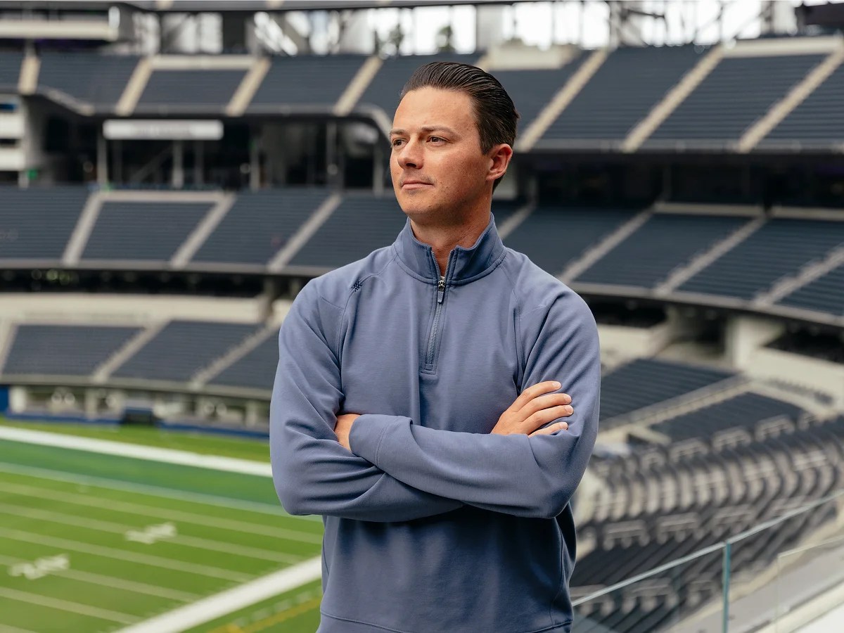 A man standing in a stadium with his arms crossed