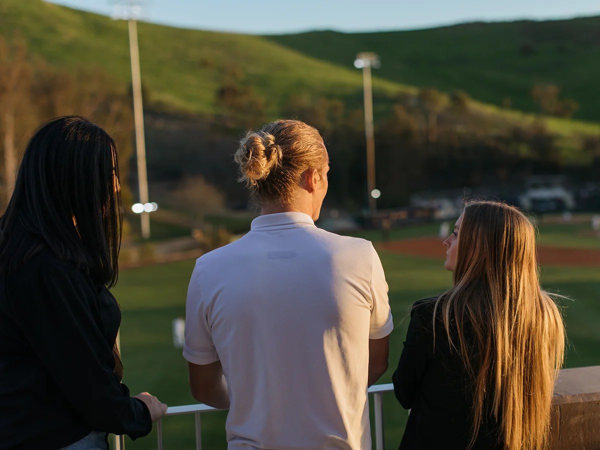 A group of people standing on a balcony overlooking a field