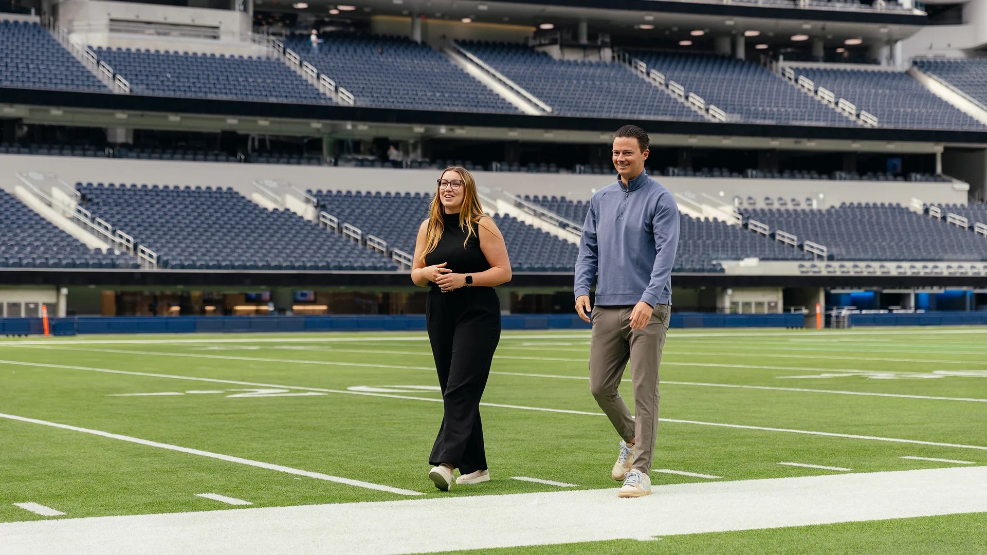 A man and woman walking on a football field