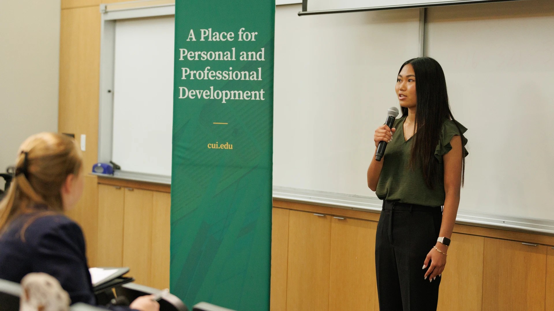 Student giving a presentation with a microphone during a business competition at Concordia University Irvine