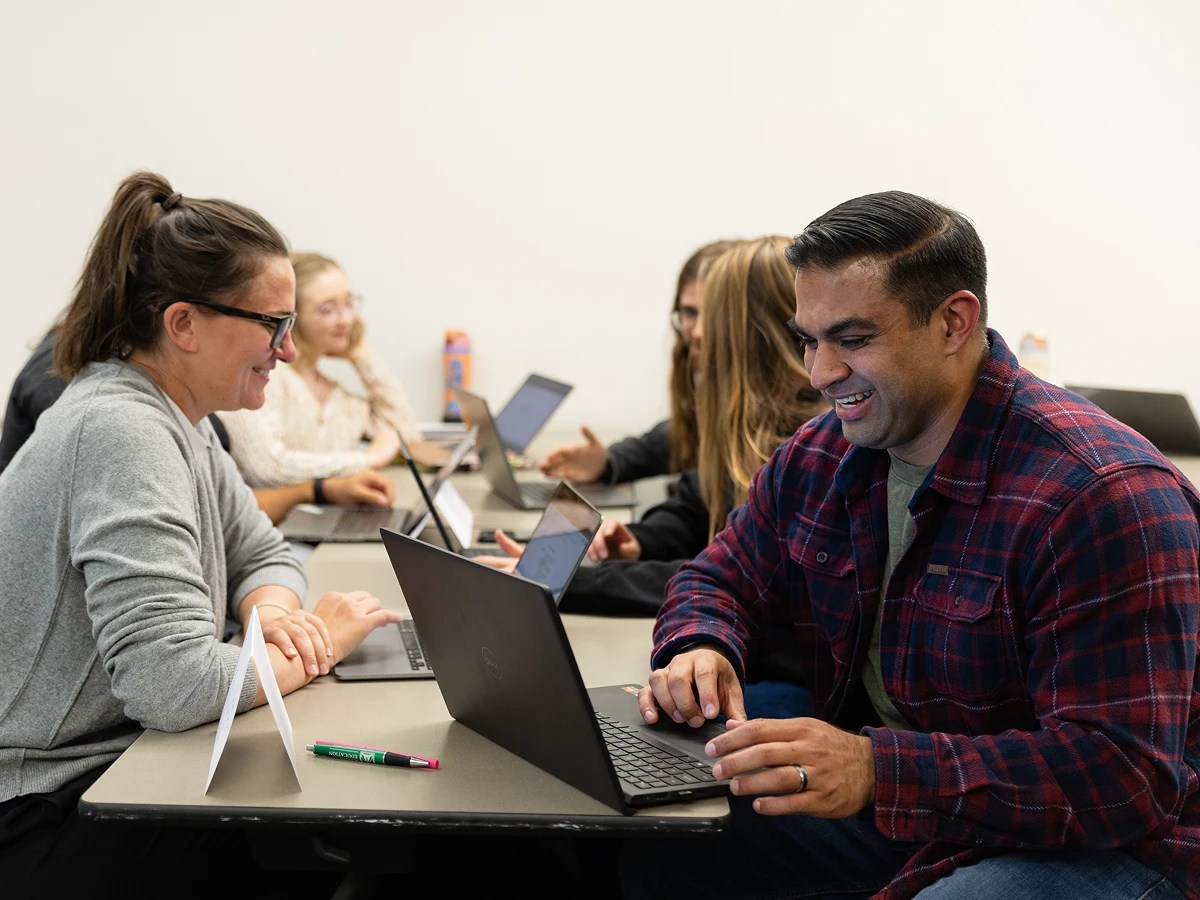 A group of people sitting at a table with laptops