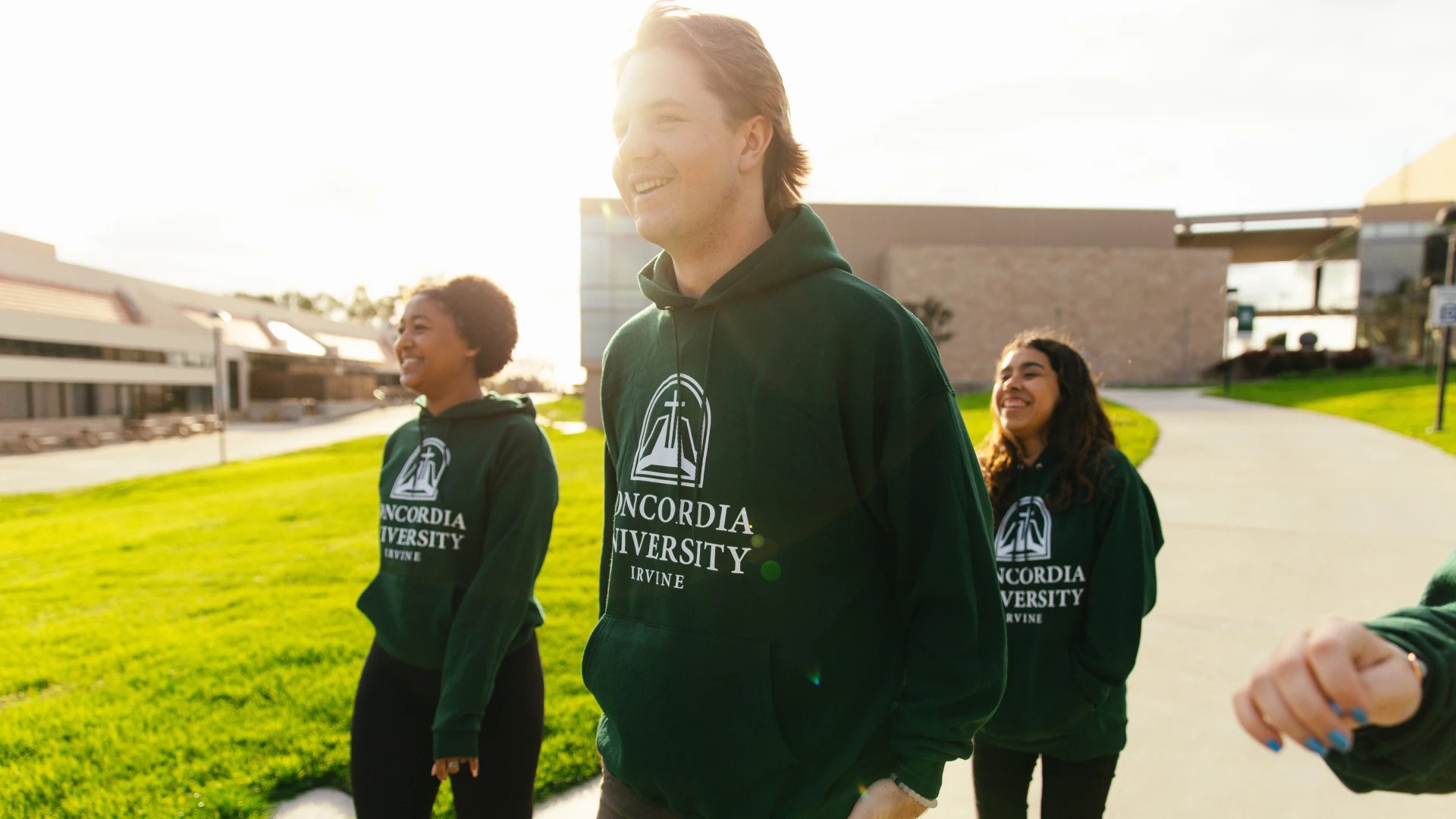 Group of students wearing Concordia University Irvine hoodies walking together on campus in the sunlight