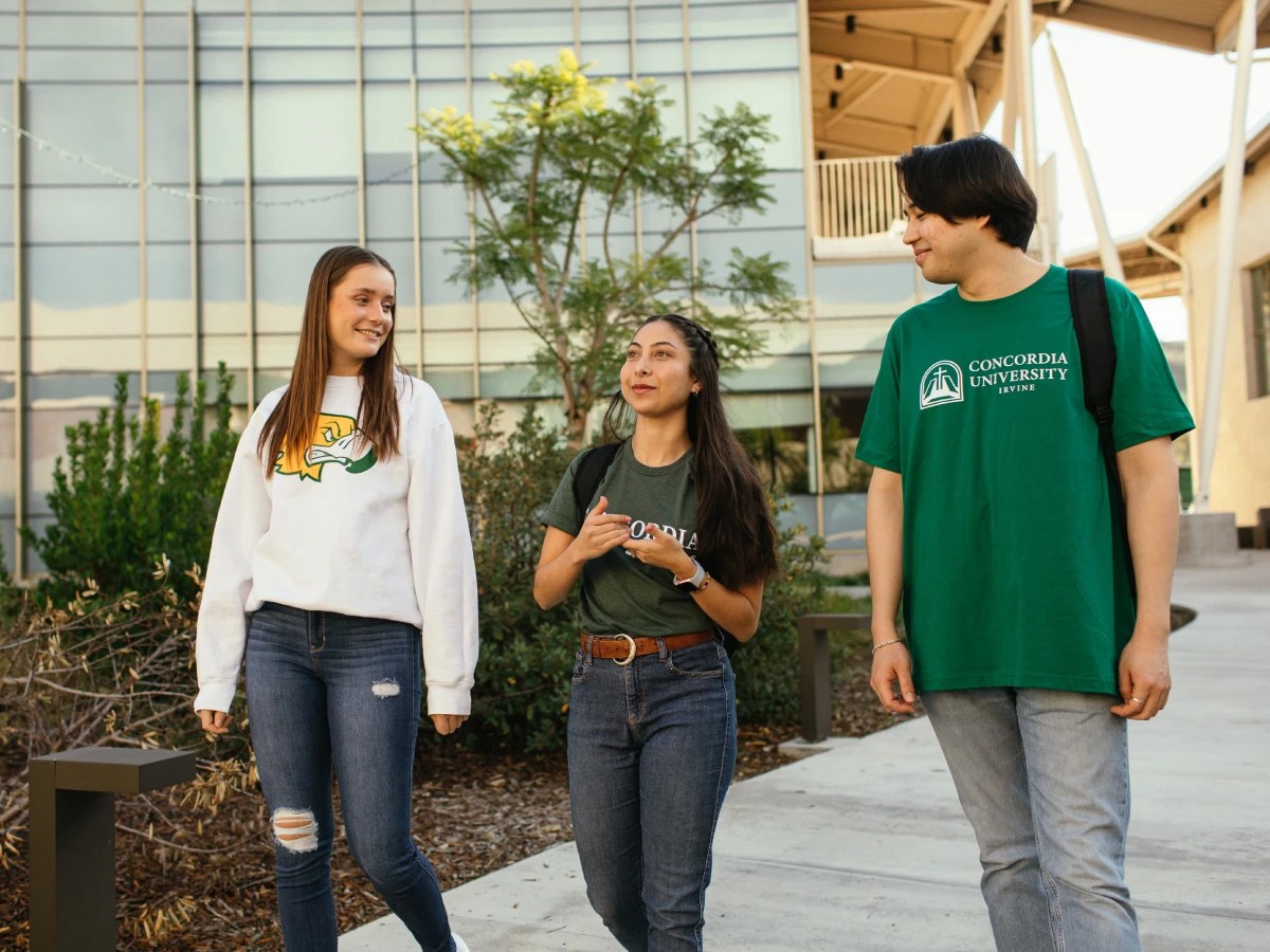 Three students walking together outside a campus building at Concordia University Irvine