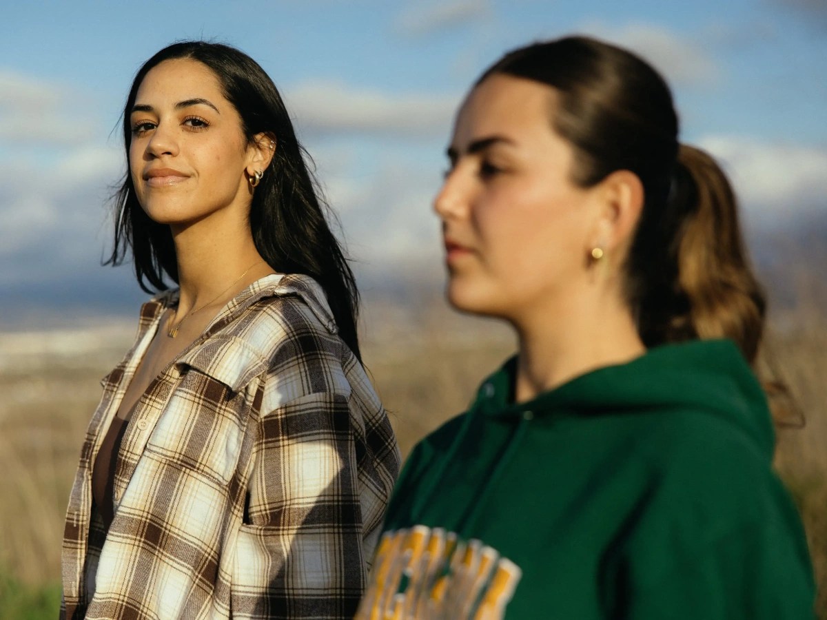 Two students standing outdoors in warm sunset light.