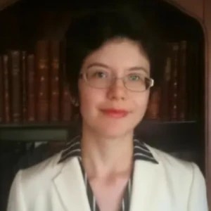 A woman wearing glasses and a white jacket