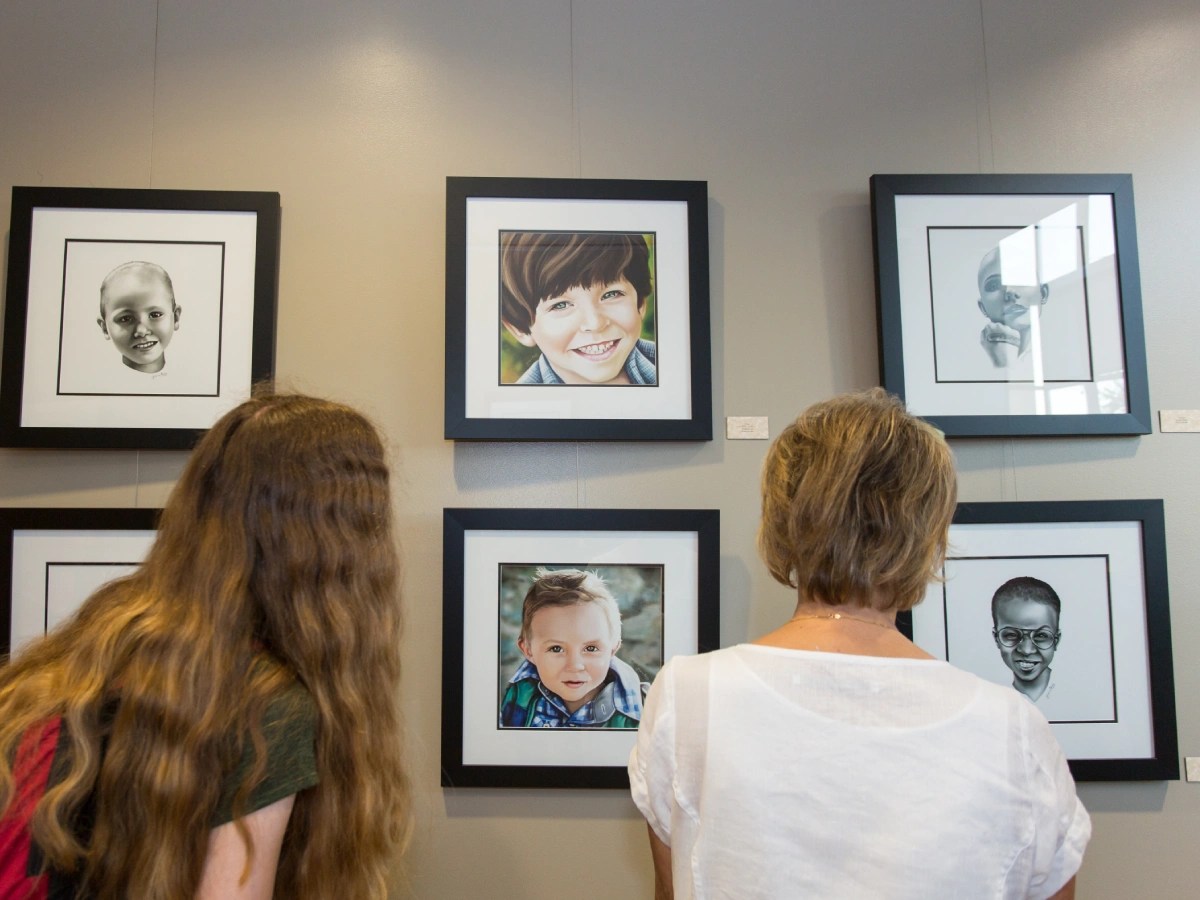 A group of people looking at pictures on the wall