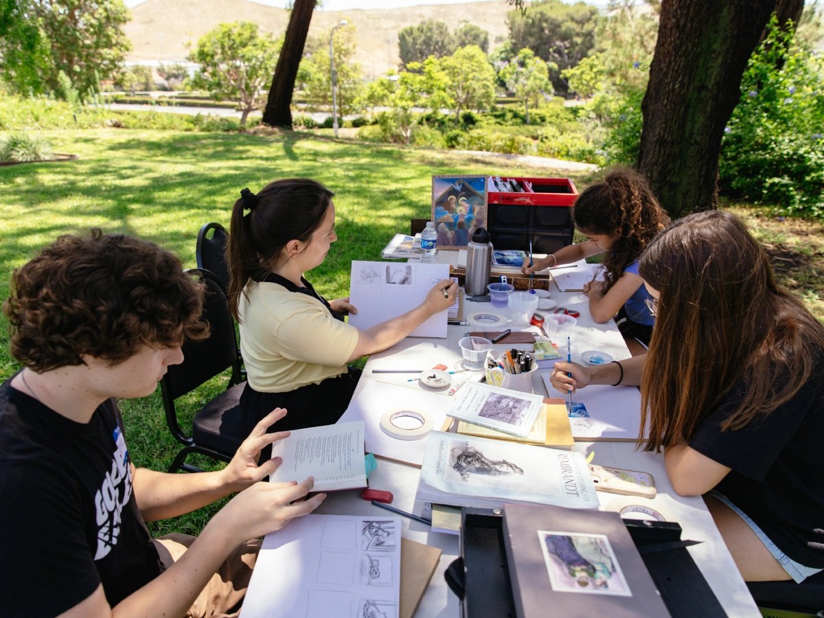 A group of people sitting at a table with art books