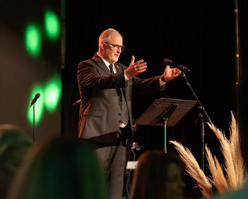 A man in a suit standing on a stage with a microphone