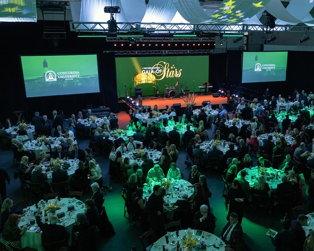 A group of people sitting at tables in a room with green lights