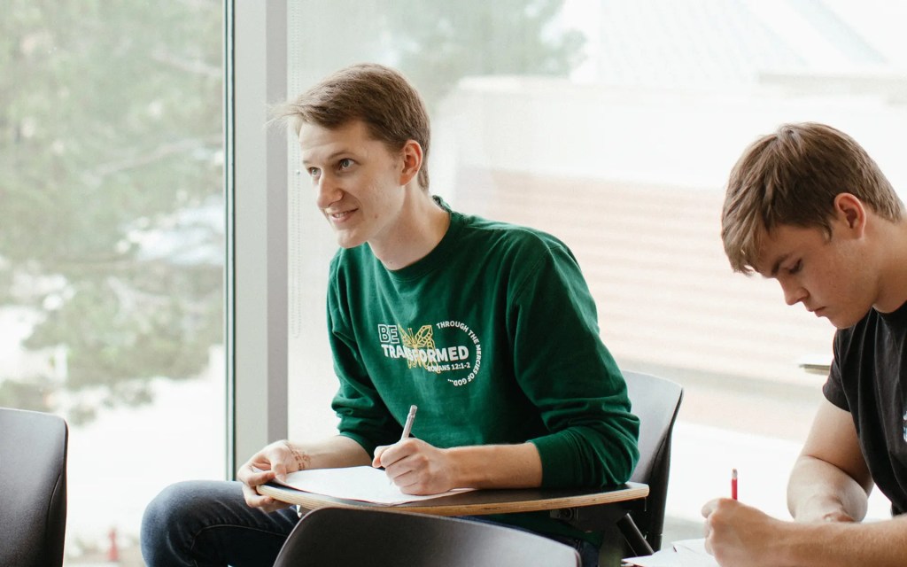 A man sitting at a desk writing on a piece of paper