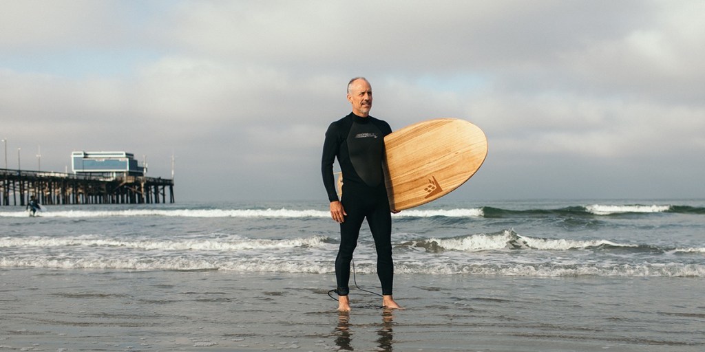 A man in a wet suit holding a surfboard