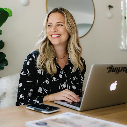 A woman smiling at a laptop