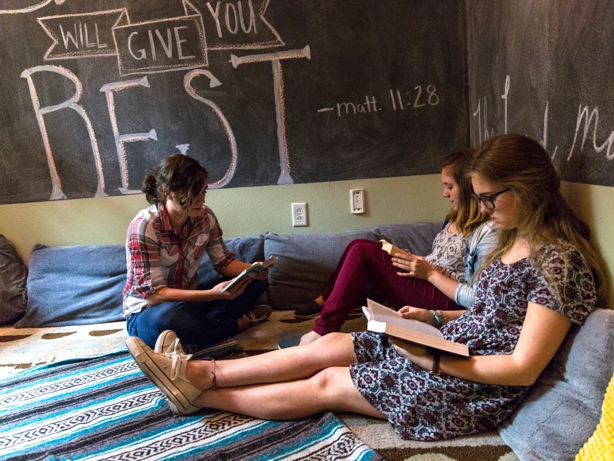 A group of women sitting on a couch reading books