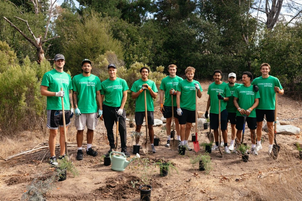 A group of people wearing green t-shirts holding shovels