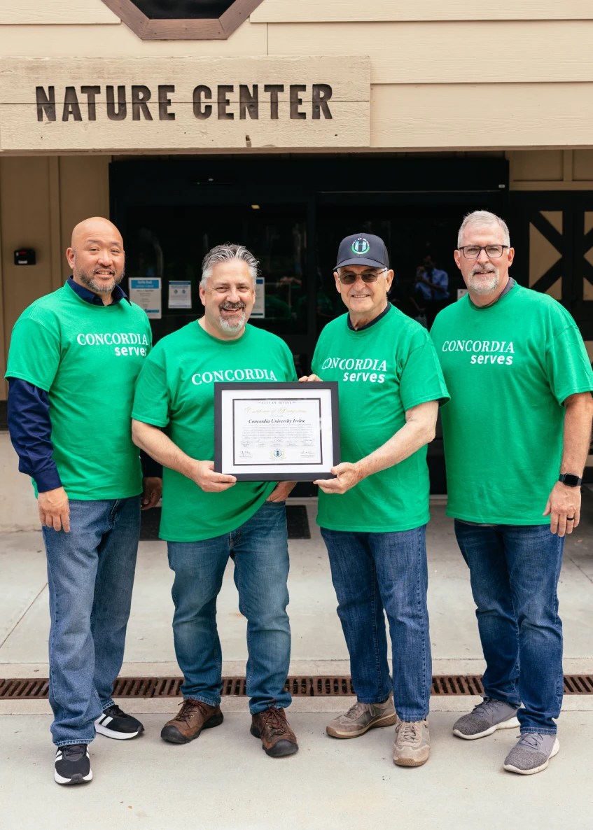A group of men in green shirts holding a certificate