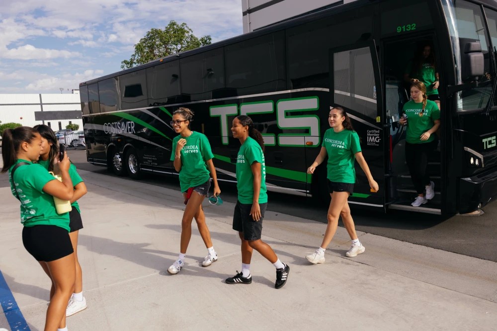 A group of people walking next to a bus