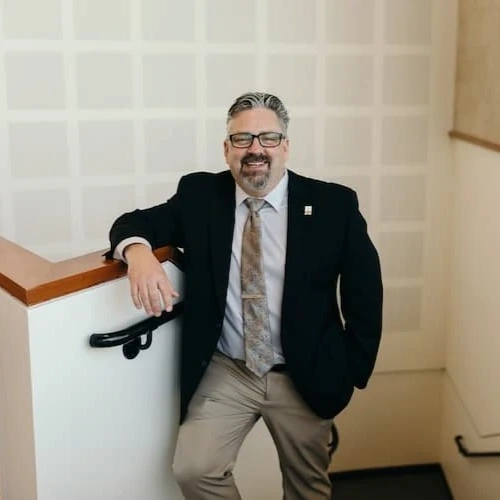 A man in a suit leaning on a railing