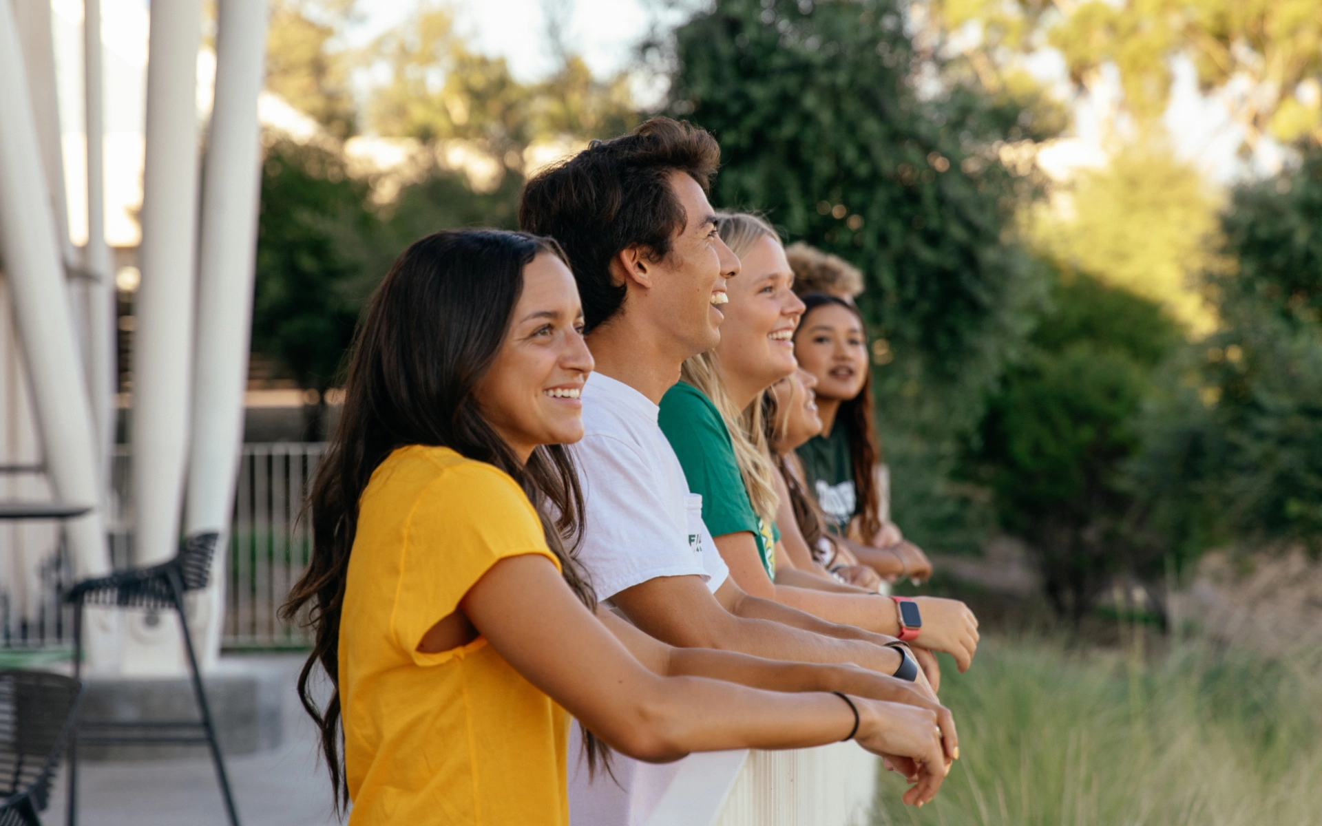 A group of people leaning on a white fence