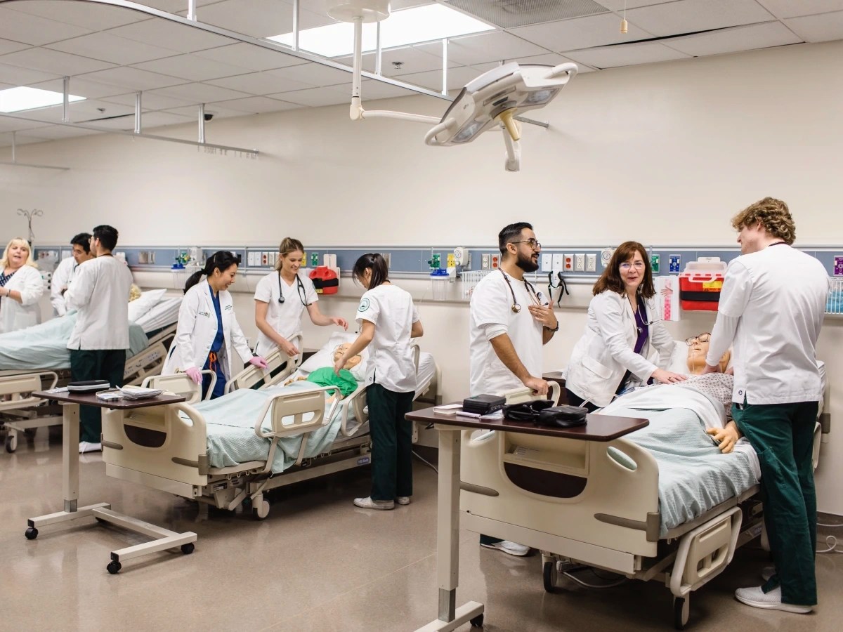 A group of people in a room with a person lying on a bed