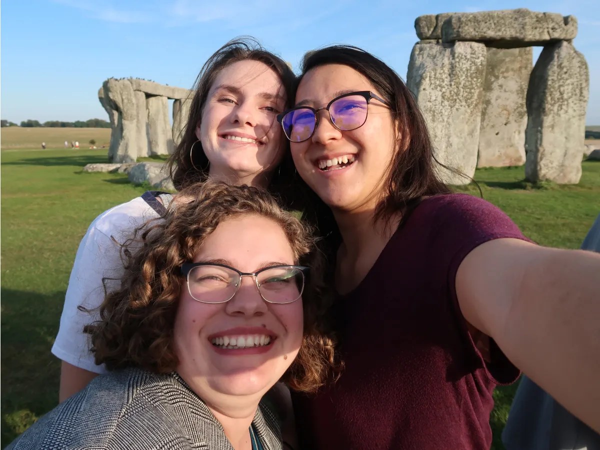 A group of women taking a selfie in front of a stone monument
