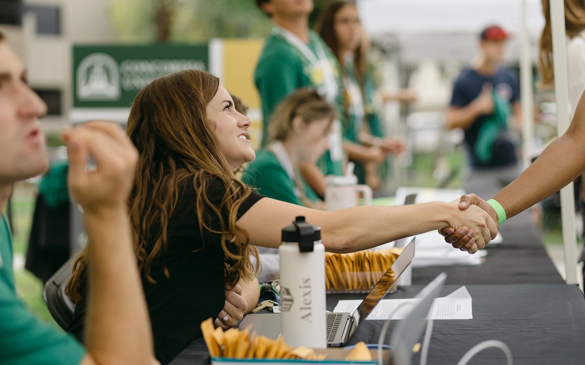 A woman shaking hands with a woman sitting at a table