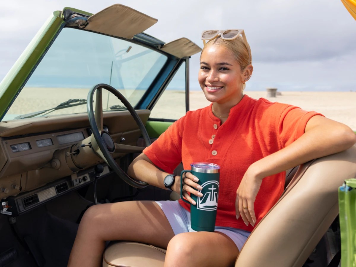 A woman sitting in a car holding a coffee cup