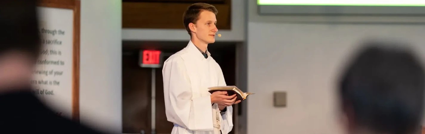 A man in a white robe holding a book