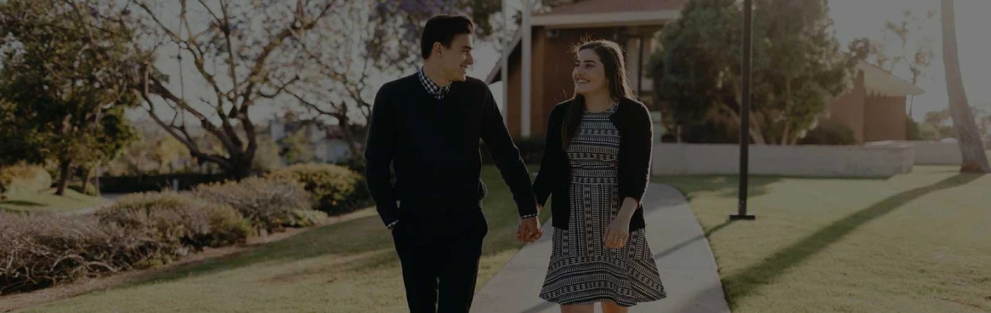 A man and woman holding hands and walking on a sidewalk