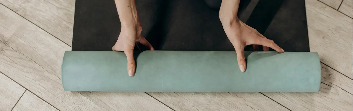 A person rolling a roll of yoga mat